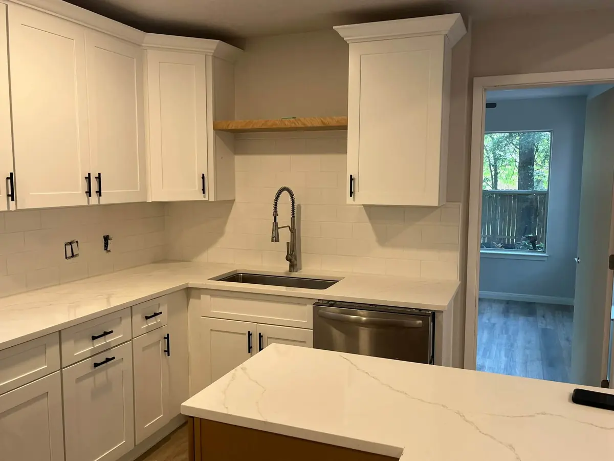 White shaker kitchen with quartz countertops and black faucet